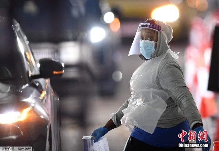 當(dāng)?shù)貢r(shí)間12月18日，英國政府公布的數(shù)據(jù)顯示，當(dāng)天英國新增奧密克戎毒株感染病例10059例。鑒于奧密克戎毒株感染病例激增，住院人數(shù)不斷上升，倫敦市長(zhǎng)宣布倫敦進(jìn)入“重大事故”狀態(tài)。圖為倫敦的一個(gè)免下車檢測(cè)中心，一名醫(yī)務(wù)工作者正準(zhǔn)備對(duì)司機(jī)進(jìn)行核酸檢測(cè)。