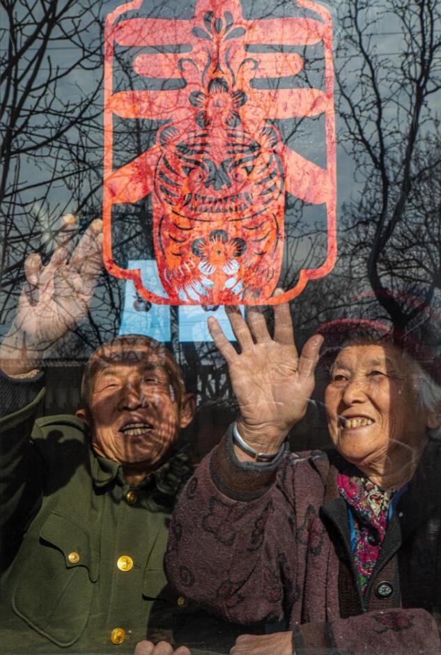 臘月里，霍州市師莊鄉(xiāng)馮南垣村村民師榮光(左)在災(zāi)后重建的新家里貼窗花。(霍州市委宣傳部供圖)