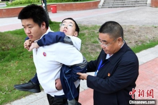 朱金祥背著鐘華強(qiáng)去教室上課的路上，也經(jīng)常碰到值班的校領(lǐng)導(dǎo)和老師前來(lái)搭把手。 卓忠偉 攝