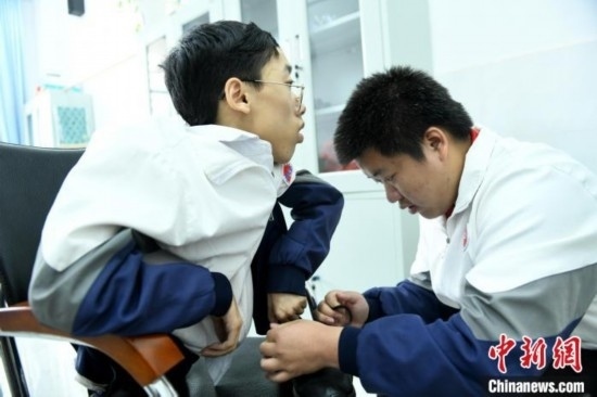 江西省南康中學(xué)北校區(qū)的高三學(xué)生朱金祥(右)正在給鐘華強(qiáng)(左)系好鞋帶。 卓忠偉 攝