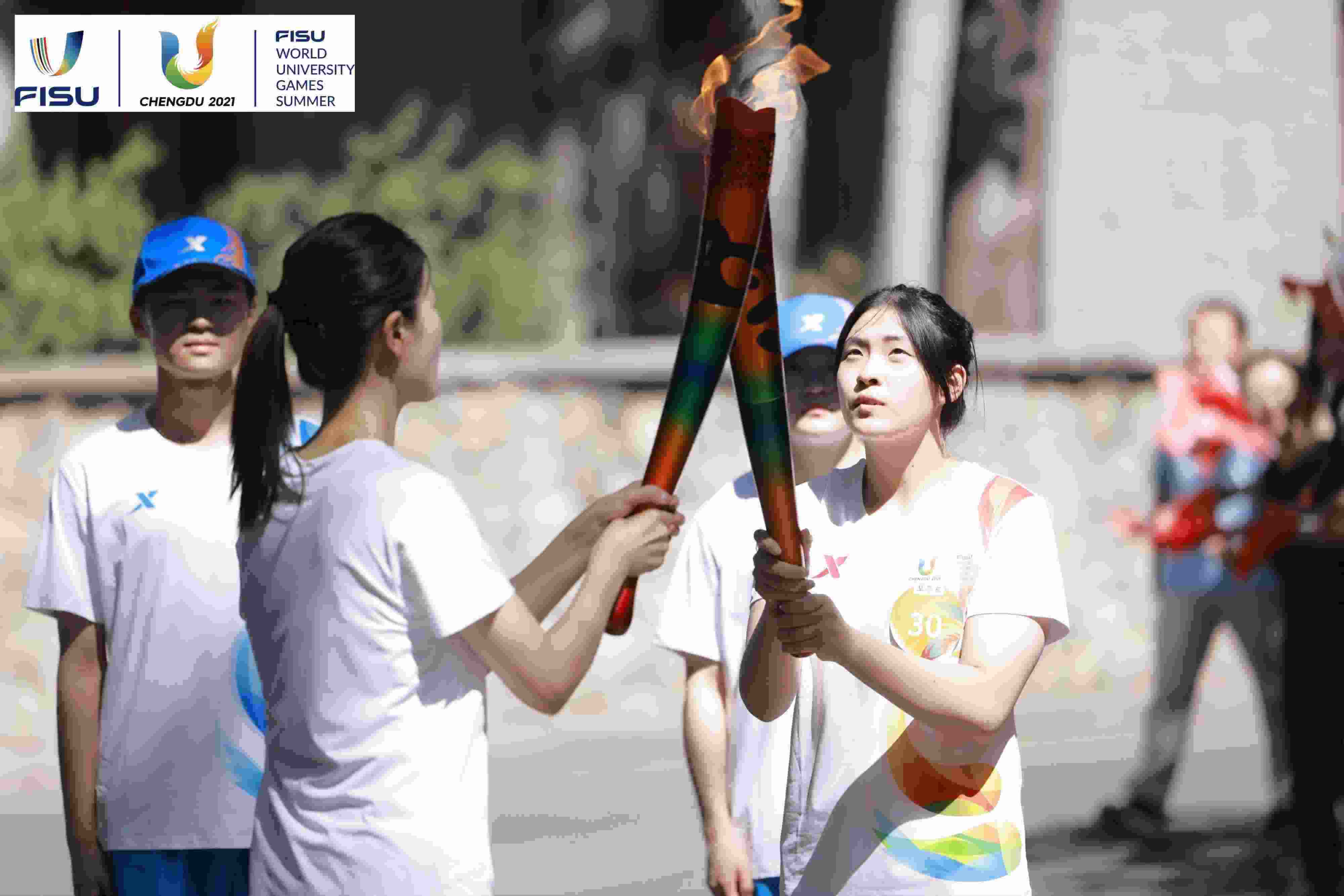 兩名大運(yùn)會(huì)火炬手進(jìn)行火炬?zhèn)鬟f。 圖片來(lái)源：成都大運(yùn)會(huì)執(zhí)委會(huì)供圖