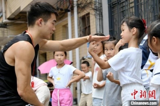 圖為大學生志愿者在組織孩子們參加體育健身活動。廖光福 攝