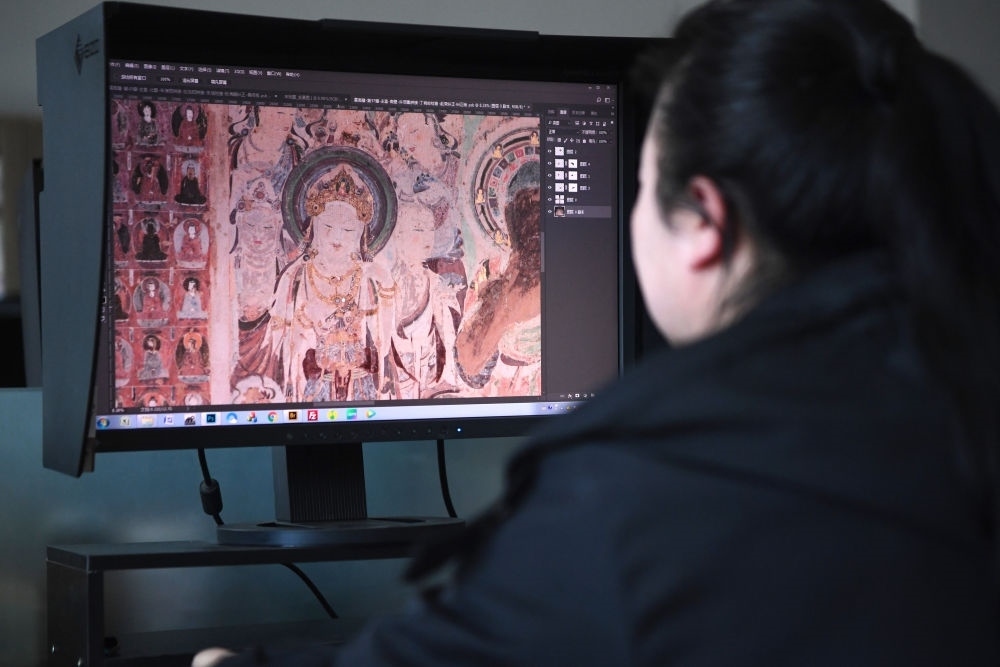 敦煌研究院文物數(shù)字化保護團隊圖像處理人員年海麗在拼接壁畫圖像（2023年4月25日攝）。數(shù)字化探索為莫高窟的保護與傳承開辟了全新路徑，數(shù)字技術讓敦煌文物走出洞窟，跨出國門，走向“永久保存、永續(xù)利用”。新華社記者 陳斌 攝