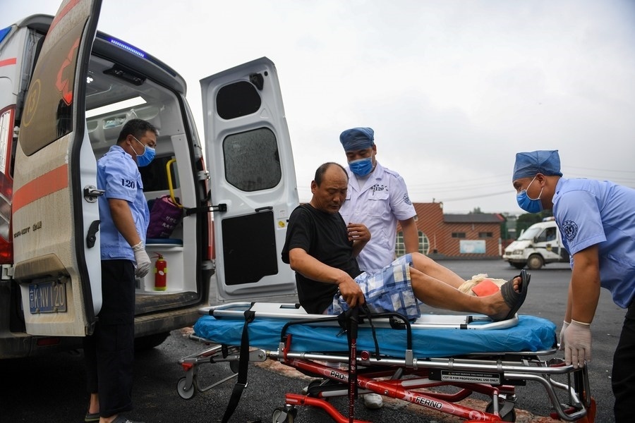 8月1日，在北京市門頭溝區(qū)妙峰山鎮(zhèn)妙峰山民族學(xué)校臨時安置點(diǎn)，北京急救中心工作人員在轉(zhuǎn)運(yùn)一名受傷村民。新華社記者 鞠煥宗 攝