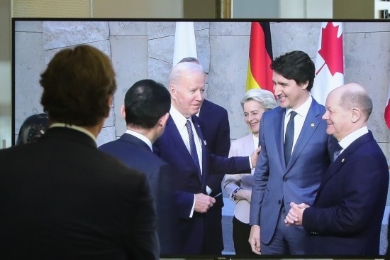 2022年3月24日，在比利時布魯塞爾的北約總部，一名男子觀看屏幕上美國總統(tǒng)拜登（右四）、歐盟委員會主席馮德萊恩（右三）、加拿大總理特魯多（右二）、德國總理朔爾茨（右一）出席七國集團峰會合影儀式的畫面。新華社記者鄭煥松攝