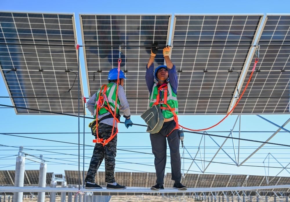 2023年7月22日，工人在位于內(nèi)蒙古杭錦旗庫布其沙漠億利生態(tài)示范區(qū)的蒙西基地庫布其200萬千瓦光伏治沙項(xiàng)目工地安裝光伏板。新華社記者 劉磊 攝