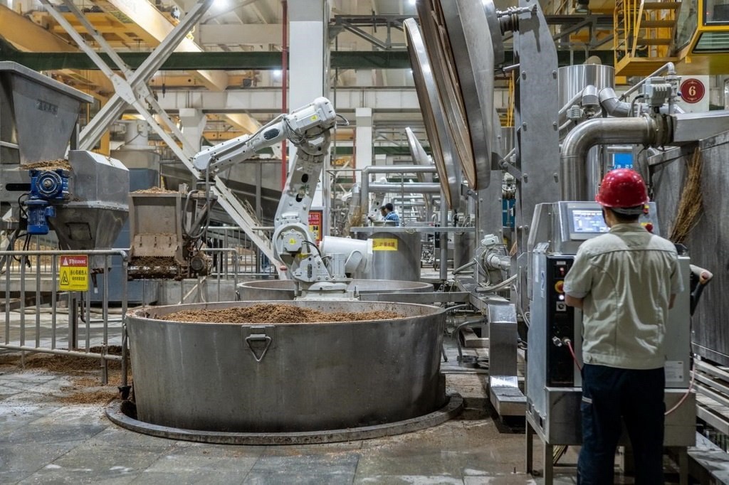 907車間里，機械臂正在撒料裝甑。嚴磊攝