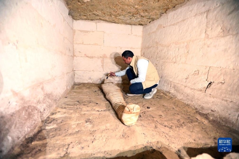 10月15日，在埃及明亞省考古現(xiàn)場，考古人員清理一座石鑿墓中的木乃伊。新華社發(fā)（艾哈邁德·戈馬攝）