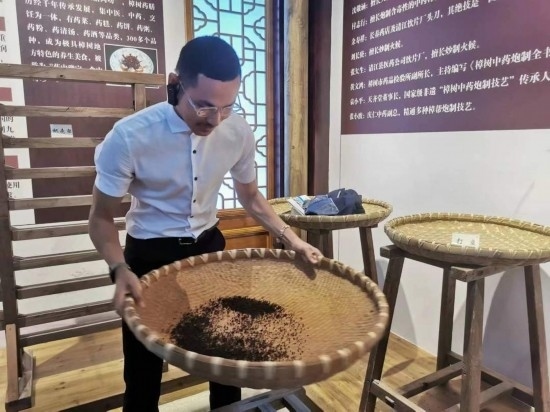 2023“一帶一路”媒體合作論壇聯(lián)合采訪團團員在非遺文化展示館體驗中藥炮制技藝。（本報記者 黃超攝）