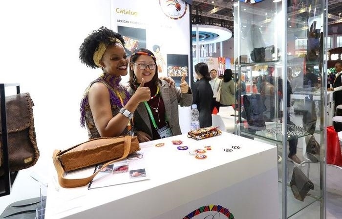 11月6日，一位參觀者（右）在第六屆進博會國家展南非展臺試戴傳統(tǒng)首飾。