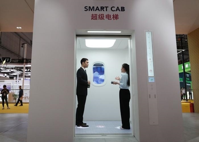 11月5日，工作人員（右）在第六屆進博會上向參觀者介紹奧的斯公司全新推出的超級電梯。