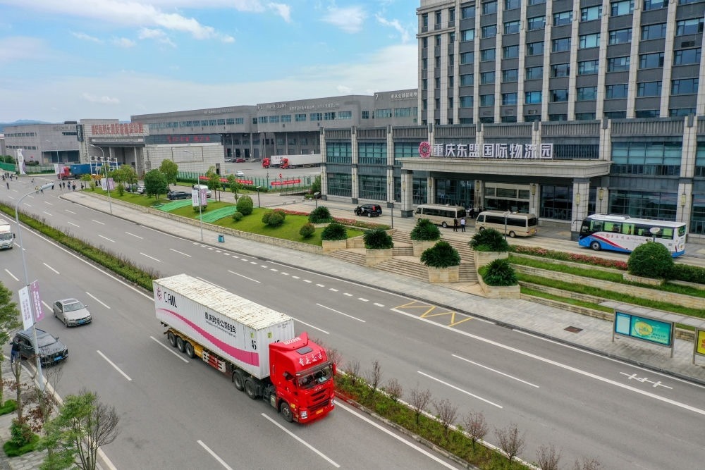 2023年10月11日，滿載筆記本電腦配件、發(fā)電機組件等產(chǎn)品的西部陸海新通道跨境公路班車從重慶南彭公路保稅物流中心駛出，將途經(jīng)廣西憑祥，直達越南（無人機照片）。新華社記者 黃偉 攝