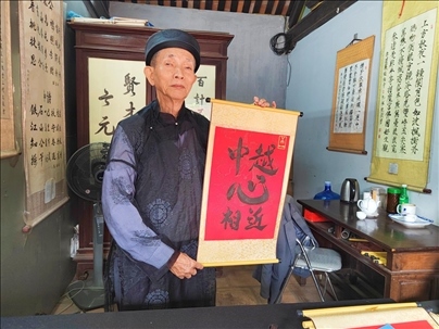 越南首都河內(nèi)文廟內(nèi)，阮明珠展示“中越心相近”書法作品。