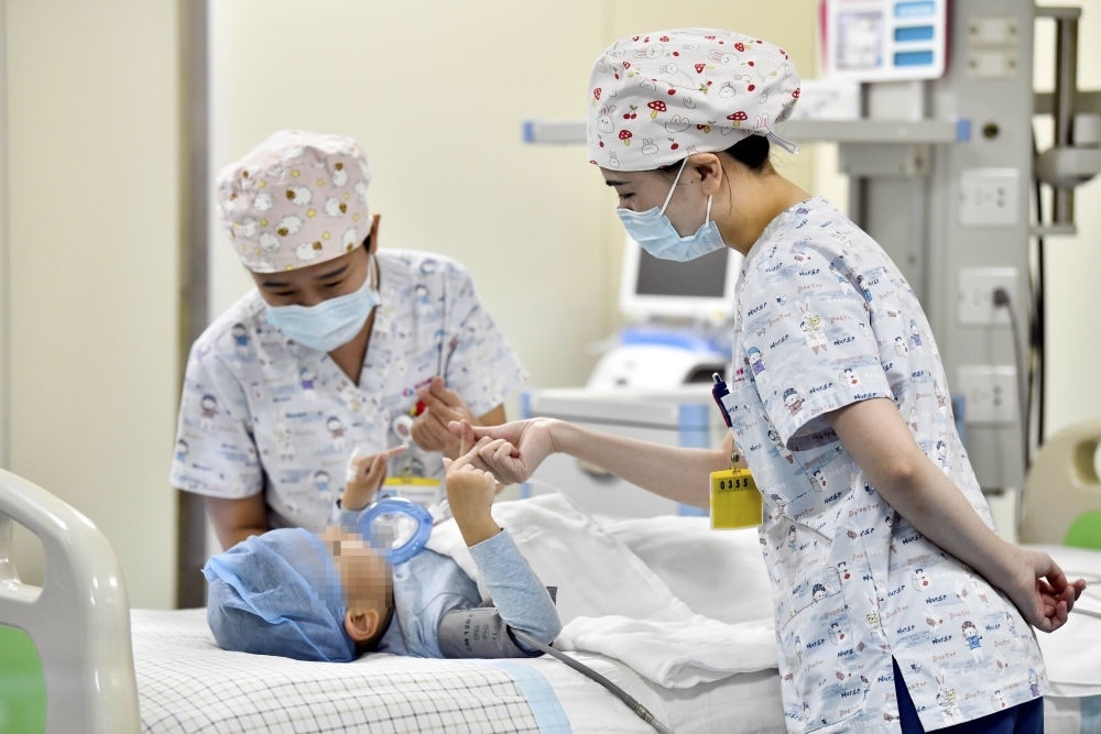 在山東省棗莊市婦幼保健院兒童ICU病房，醫(yī)護人員為完成靶向治療藥物諾西那生鈉的4歲脊髓性肌萎縮癥患兒加油鼓勁（2022年1月1日攝）。諾西那生鈉注射液是我國首個獲批治療脊髓性肌萎縮癥的進口藥物，2019年進入中國市場時，每針價格近70萬元。在2021年國家醫(yī)保目錄藥品談判中，以3.3萬元每針的價格進入新版醫(yī)保藥品目錄。新華社記者 郭緒雷 攝