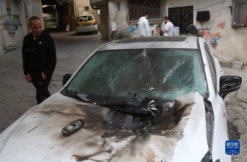 12月17日，在約旦河西岸城市圖勒凱爾姆附近的一處難民營，人們查看在沖突中損毀的車輛。新華社發(fā)（尼達(dá)爾·艾仕塔耶?dāng)z）