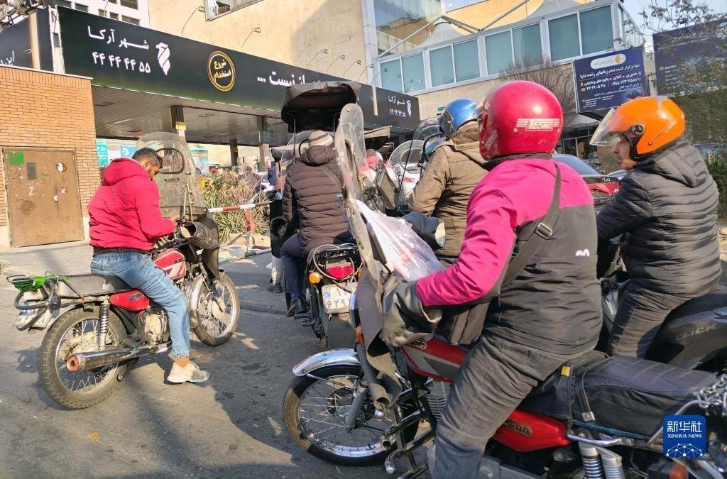 12月18日，摩托車在伊朗首都德黑蘭的一家加油站外等待加油。新華社記者 沙達提 攝