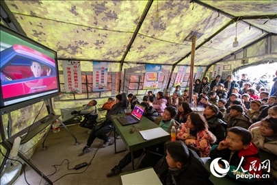 12月22日，在積石山縣大河家鎮(zhèn)大河村安置點，陸軍76集團軍某旅搭建的“臨時學(xué)校”內(nèi)，小朋友正在看動畫片。人民網(wǎng)記者 翁奇羽攝