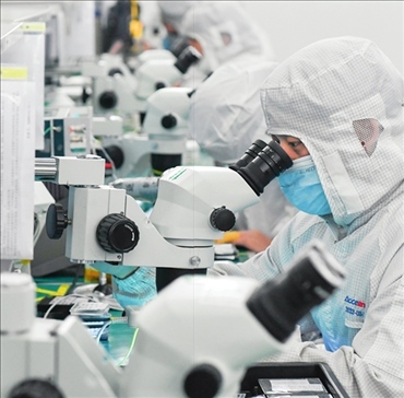 在位于武漢中國(guó)光谷的光電器件研發(fā)制造商——武漢光迅科技股份有限公司生產(chǎn)車(chē)間內(nèi)，技術(shù)人員在光模塊生產(chǎn)線(xiàn)作業(yè)（2023年4月11日攝）。程敏攝/本刊