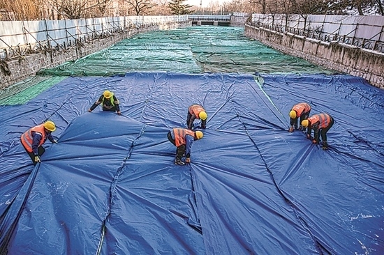 1月3日，房山區(qū)東風(fēng)街道，工人正在修復(fù)的河道內(nèi)給混凝土鋪設(shè)保溫布。