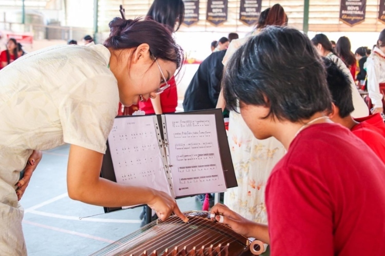 志愿者教師指導學生彈奏古箏?；顒又鬓k方供圖