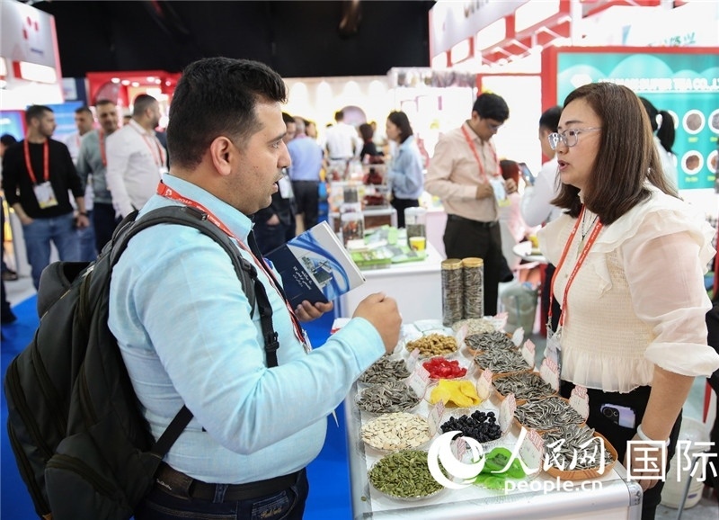 圖為一家中國干果參展企業(yè)代表與采購商洽談。人民網(wǎng) 塔里克·易卜拉欣攝