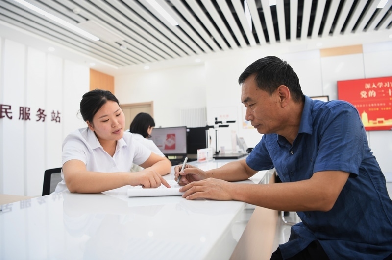 2023年5月23日，河北雄安新區(qū)容東片區(qū)南文營(yíng)社區(qū)居民（右）在社區(qū)便民服務(wù)站辦理業(yè)務(wù)。