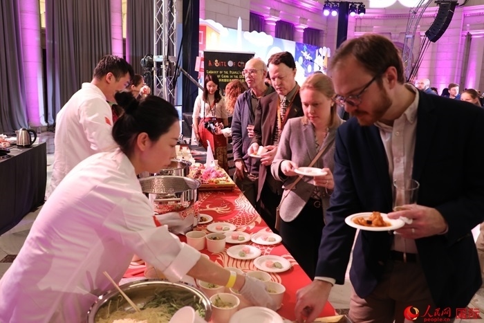 當(dāng)?shù)貢r(shí)間3月7日晚，華盛頓聯(lián)合車站廣場(chǎng)舉行駐美使團(tuán)“使館主廚挑戰(zhàn)賽”。圖為當(dāng)?shù)孛癖娫谥袊?guó)展臺(tái)前體驗(yàn)中國(guó)美食。人民網(wǎng)記者 李志偉攝