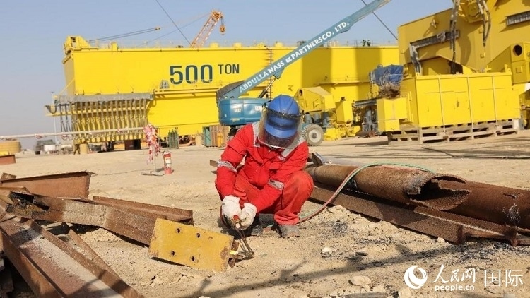 工人正在龍門吊吊裝現(xiàn)場切割金屬件。人民網(wǎng)記者管克江攝