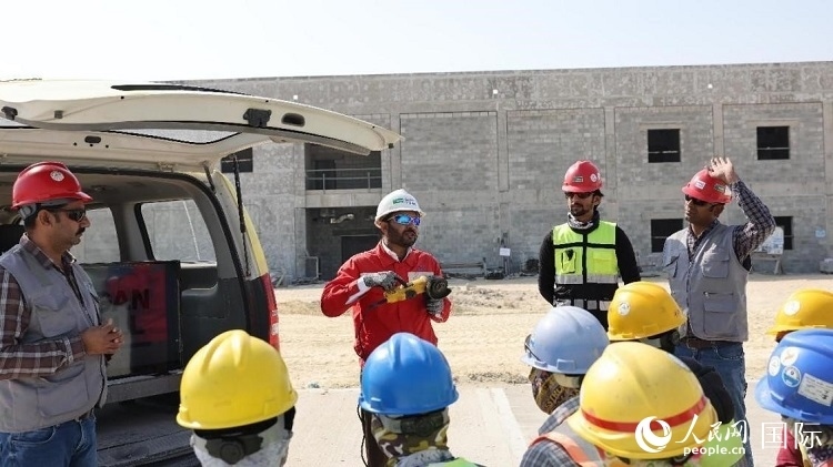 穆薩瓦爾(圖中紅衣人）現(xiàn)場演示工具操作規(guī)范。人民網(wǎng)記者 管克江攝