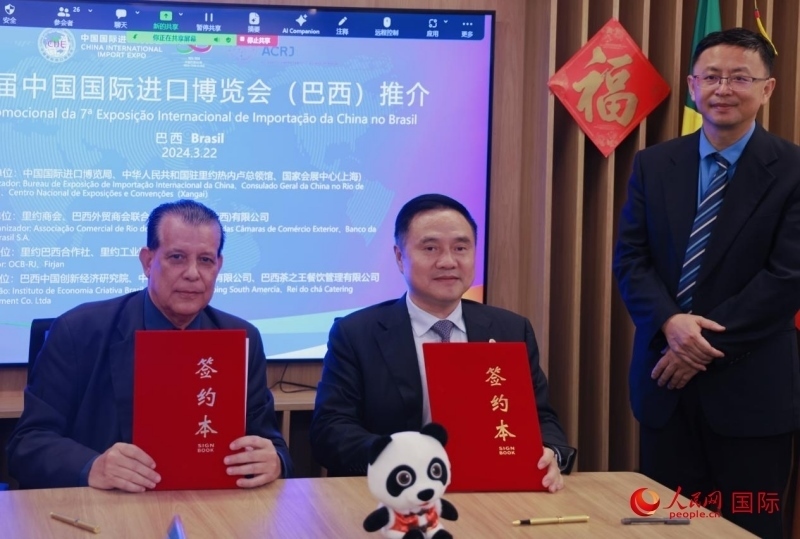 巴西外貿商會聯(lián)合會會長阿代爾·羅伯托（左）與中國國際進口博覽局副局長吳政平（中）現(xiàn)場簽訂協(xié)議。人民網記者 宋亦然攝