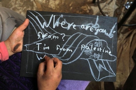 2023年12月28日，一名學(xué)生在加沙地帶南部城市拉法一所學(xué)校的臨時(shí)教室中寫下“我來自巴勒斯坦”的字樣。新華社發(fā)（里澤克·阿卜杜勒賈瓦德攝）