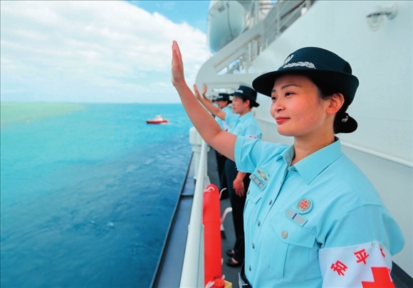 中國(guó)海軍“和平方舟”號(hào)醫(yī)院船結(jié)束訪問湯加時(shí)，任務(wù)官兵中的文職人員向歡送人群揮手告別（2023年8月4日攝）。徐巍攝/本刊