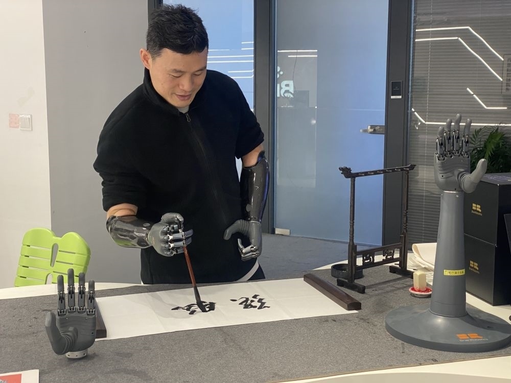 2024年3月29日，在浙江強(qiáng)腦科技有限公司展廳內(nèi)，失去雙手的產(chǎn)品體驗(yàn)官倪敏成依靠智能仿生手寫(xiě)毛筆字。新華社記者 魏一駿 攝