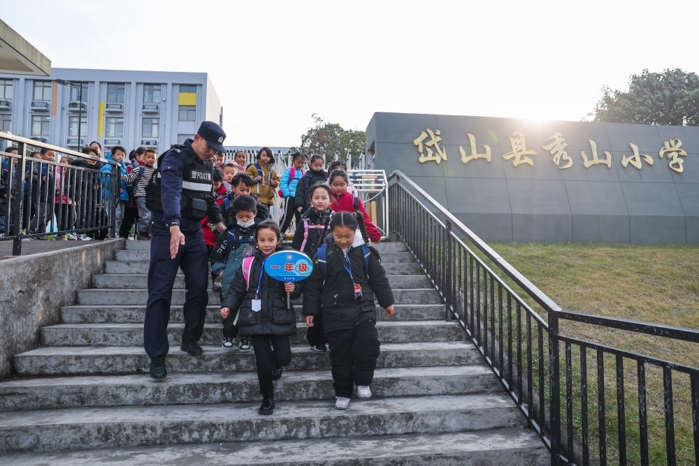 2023年12月20日，秀山派出所民警在秀山小學放學時間參與“護學崗”維持秩序，同時接獨自放學的學生去“民生小鋪”。浙江省舟山市岱山縣公安局秀山派出所聯(lián)合鄉(xiāng)鎮(zhèn)、社區(qū)成立“民生小鋪”，為當?shù)鼐用?、外來務工人員及其子女等服務，協(xié)助解決外來務工人員在工作、生活等方面的矛盾和問題，助力鄉(xiāng)鎮(zhèn)基層治理。新華社記者 徐昱 攝
