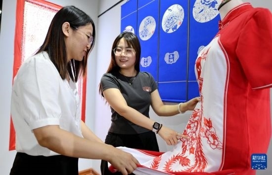 5月31日，在衡水市阜城縣一家剪紙工作室，游客在觀賞帶有剪紙元素的旗袍。