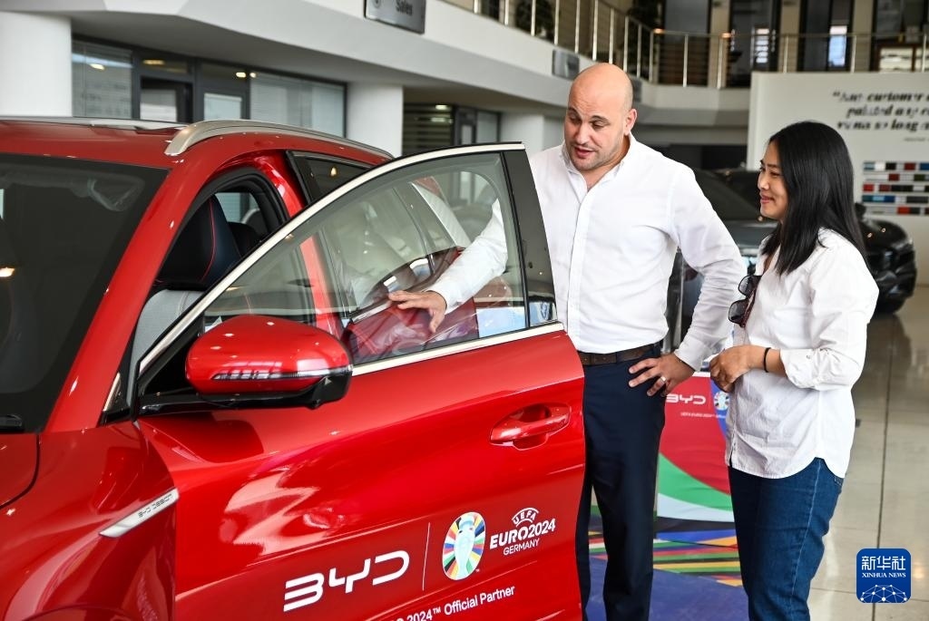 2024年5月29日，在馬耳他比爾基卡拉，馬耳他哈桑-扎米特汽車公司首席執(zhí)行官德古阿拉（左）介紹一輛比亞迪純電動(dòng)汽車。新華社發(fā)（喬納森·博格 攝）