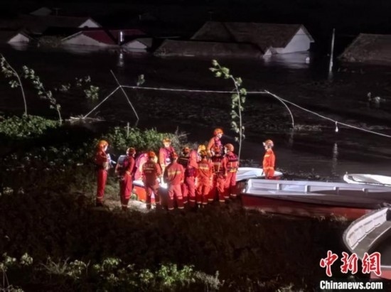  7月6日凌晨3時，在湖南岳陽華容縣團洲垸洞庭湖一線堤防，救援人員剛剛完成一次救援任務(wù)，遠處是被淹的民房。中新社記者 白祖偕 攝