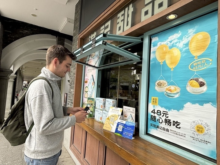來自德國的留學(xué)生理查德在杭州西湖邊一家商鋪使用支付寶掃碼支付（2024年4月11日攝）。新華社發(fā)