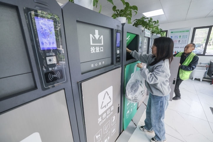 2024年4月10日，在浙江省湖州市吳興區(qū)飛英街道新華府小區(qū)內(nèi)，居民在垃圾分類智能系統(tǒng)的指導(dǎo)下進(jìn)行垃圾分類投放，居民的投放情況將實(shí)時(shí)匯總到智慧服務(wù)平臺(tái)，會(huì)有相應(yīng)的積分獎(jiǎng)勵(lì)。新華社記者 徐昱 攝