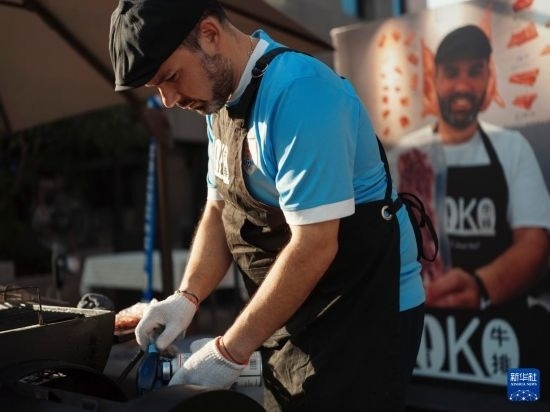7月19日，在蕪湖古城，馬丁在當(dāng)天舉行的啤酒節(jié)上制作牛排。新華社發(fā)（繆雨晨 攝）
