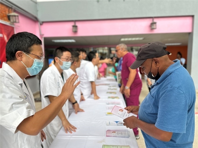 援圭醫(yī)療隊(duì)隊(duì)員們?cè)趩?dòng)儀式上為當(dāng)?shù)孛癖姺职l(fā)宣傳手冊(cè)。中國援助圭亞那醫(yī)療隊(duì)供圖