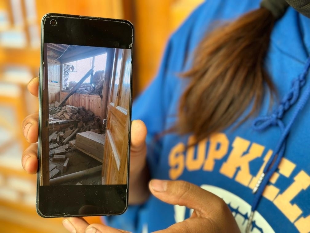 圖為7月17日拉毛東智在手機(jī)上找出地震后房屋受損的照片。新華社記者 張子琪 攝