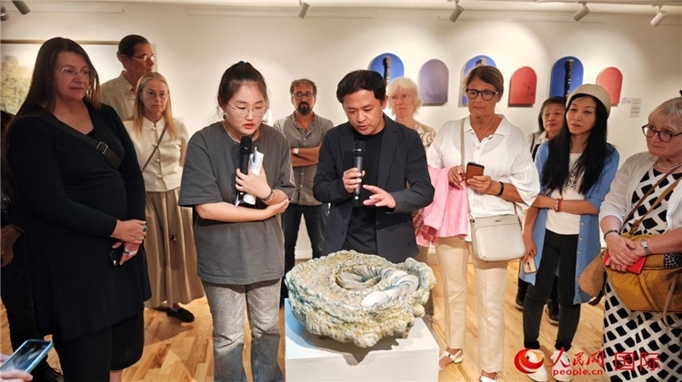 參展人、景德鎮(zhèn)陶瓷大學(xué)設(shè)計(jì)藝術(shù)學(xué)院副院長(zhǎng)余劍峰（中）向來賓介紹參展作品。人民網(wǎng)記者 殷淼攝