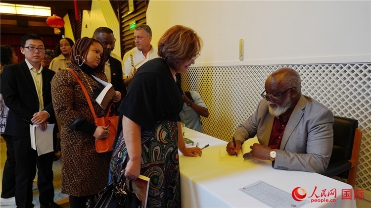 譚哲理在活動現(xiàn)場簽名贈書。人民網(wǎng) 劉暢攝