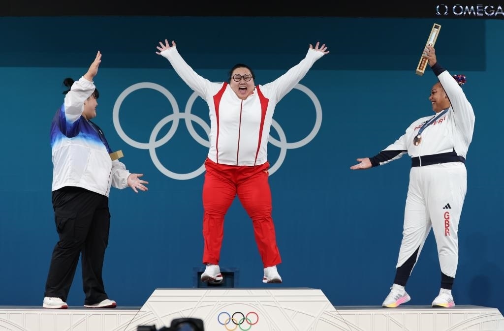 中國選手李雯雯（中）在巴黎奧運(yùn)會(huì)舉重女子81公斤以上級(jí)頒獎(jiǎng)儀式中登上領(lǐng)獎(jiǎng)臺(tái)（2024年8月11日攝）。新華社記者 楊磊 攝