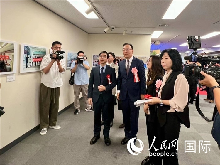 中國(guó)國(guó)際航空日韓地區(qū)支社支社長(zhǎng)馮力為中國(guó)駐日本大使館臨時(shí)代辦施泳等嘉賓介紹展出圖片。人民網(wǎng) 許可攝