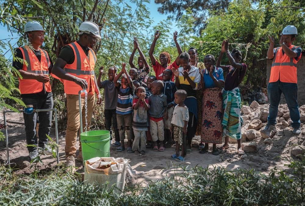 2023年6月13日，在坦桑尼亞姆萬扎省米松圭，工作人員接通水管后贏得當(dāng)?shù)鼐用窆恼茪g呼。新華社記者 王冠森 攝