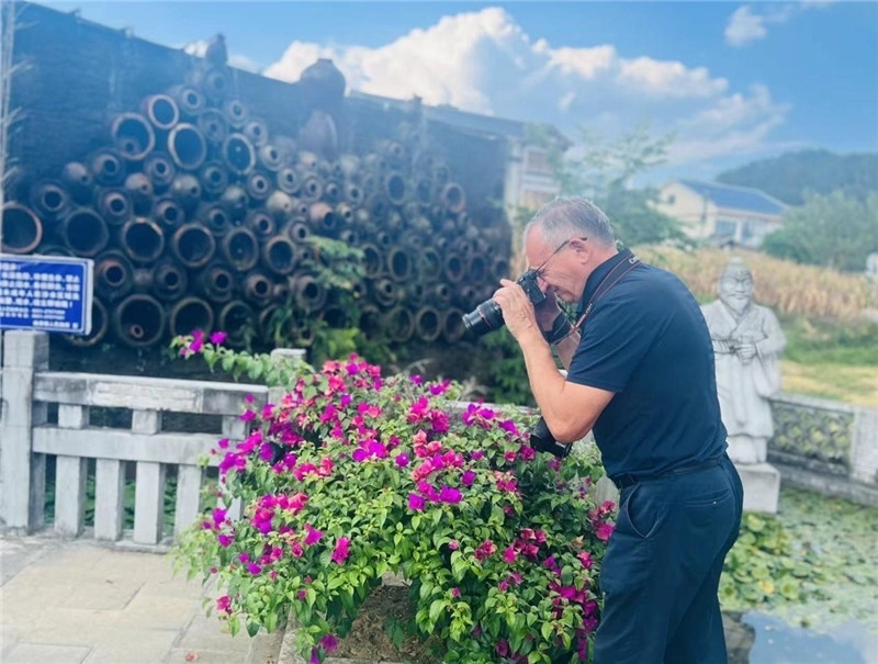 遠(yuǎn)處黔北民居錯落有致，近處一只黑色的蝴蝶穿梭于粉紫色三角梅花叢間隙，與俄羅斯“大歐亞”總編輯弗拉基米爾·別列日內(nèi)赫的鏡頭玩起了捉迷藏，“你追我逃，不亦樂乎”。（張亞欣攝）