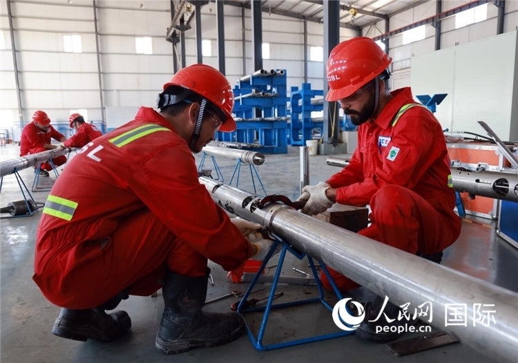 中伊員工共同在檢修鉆井設(shè)備。人民網(wǎng)記者管克江攝