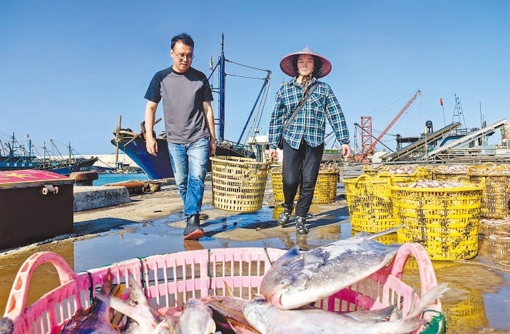 許小斌（左）和漁民一起搬運(yùn)海鮮。本報(bào)記者 付 文攝